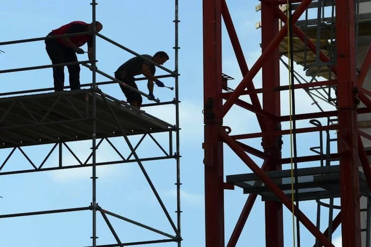 Zwei Arbeiter sind auf einer Baustelle mit dem Aufbau eines Ger¸stes besch‰ftigt. Foto: Roland Holschneider/Archiv