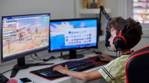 Teenager sitzt vor mehreren Monitoren und spielt "Fortnite"