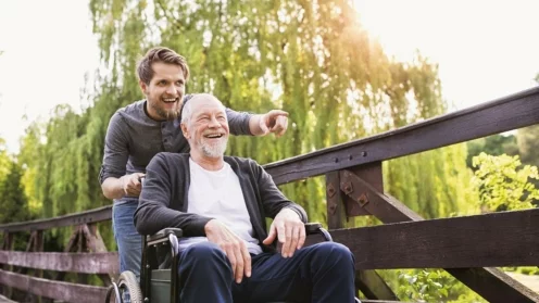 Sohn läuft mit Vater im Rollstuhl