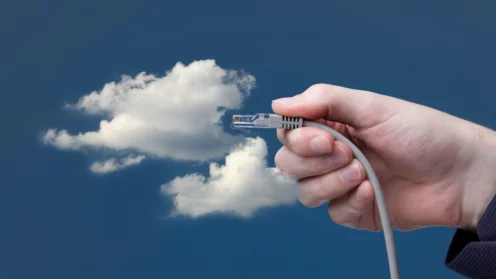 Eine weiße Wolke auf blauem Hintergrund und davor hält eine Hand einen Stecker