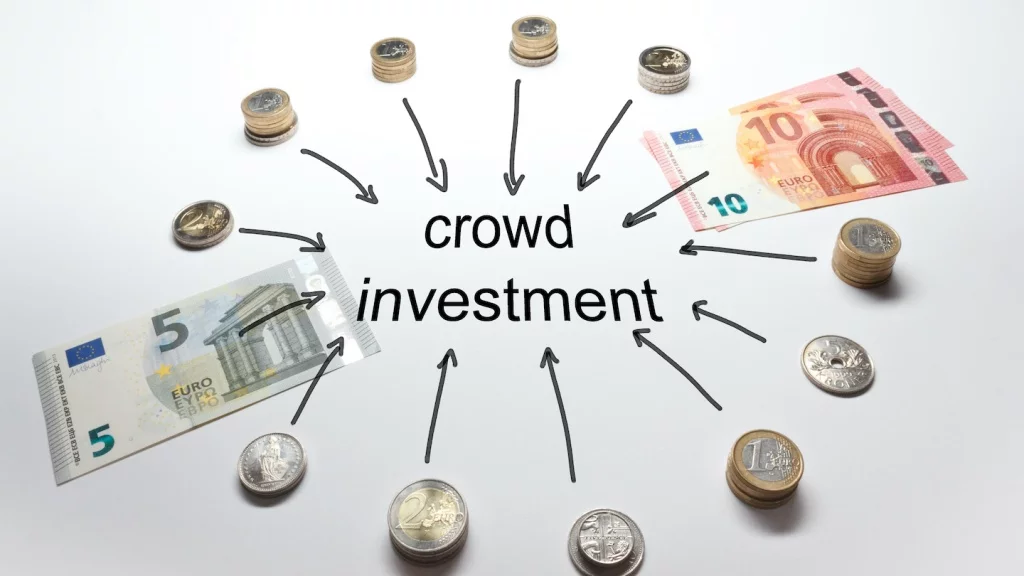 Kreis aus Geldscheinen und Münzen um das Wort Crowdinvesting