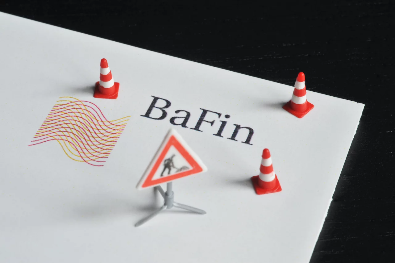 Logo der BaFin mit Baustellenschild und rot-weißen Hütchen