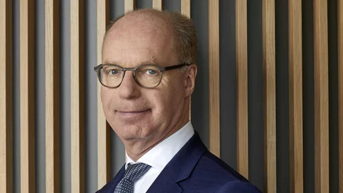 Lloyd Fonds CEO Achim Plate vor einer Wand mit senkrechten Holzleisten