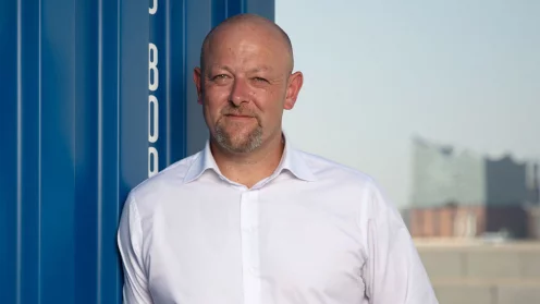 Jürgen Kestler, Geschäftsführer Solvium Capital Vertriebs GmbH, lehnt an einem Container. Im Hintergrund die Elbphilharmonie in Hamburg.