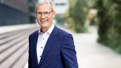 Dr. Thomas Mann - mit Brille, weißem Hemd und blauem Sakko lächelt in die Kamera