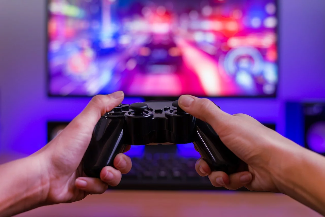 Joypad in der Hand. Spielkonzept. Computerdisplay mit Rennspiel und RGB-Licht im Hintergrund.