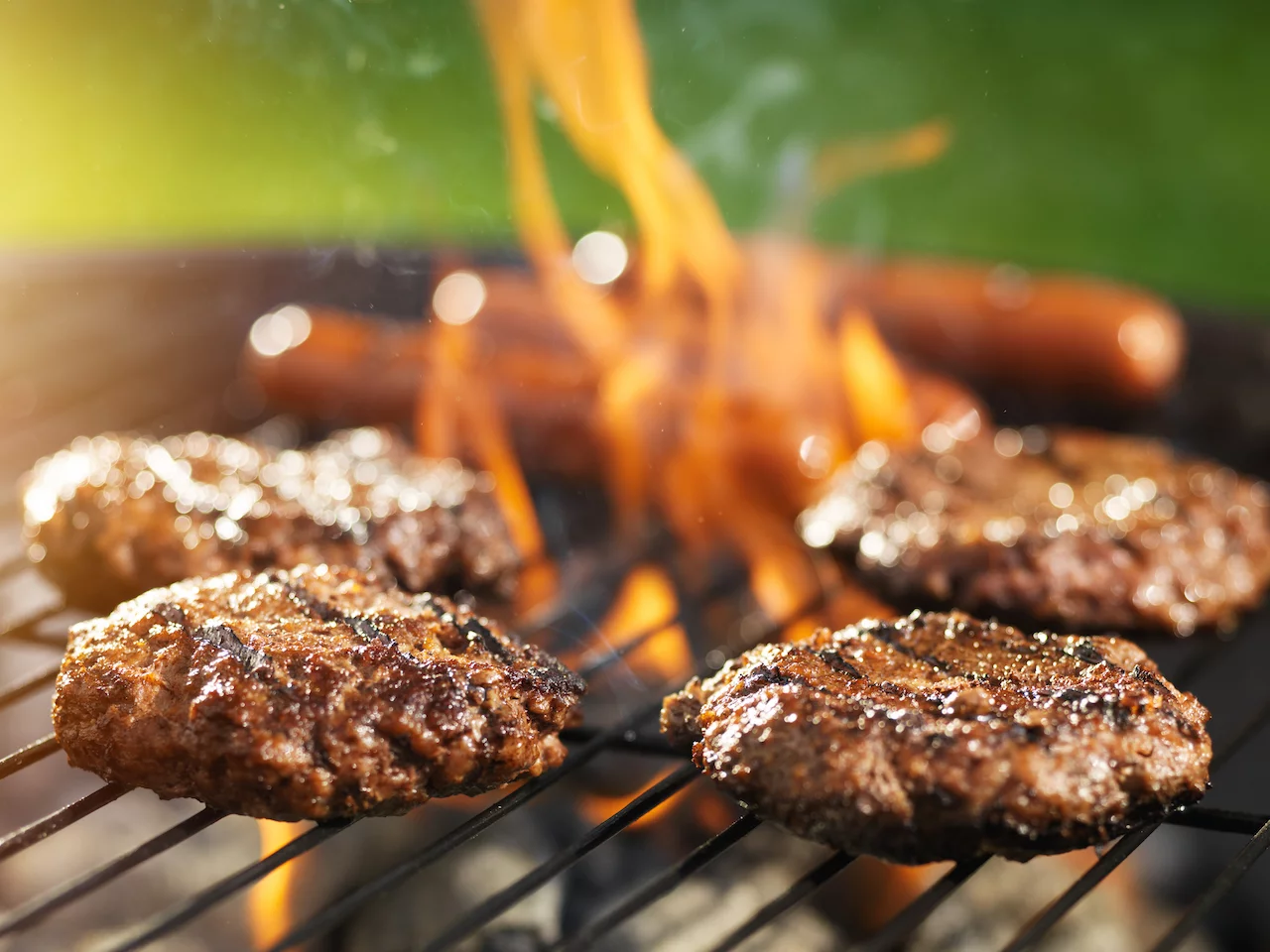 Hamburger und Hotdogs auf dem Grill, der Flammen wirft