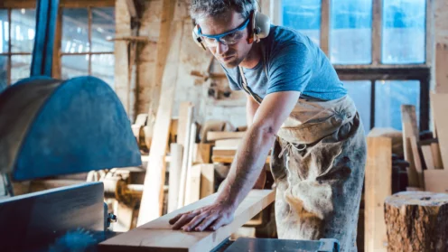 Zimmermann arbeitet mit der Kreissäge an Holz