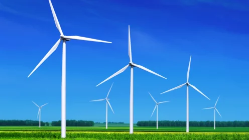 Windraeder auf gruenen Wiesen vor blauem Himmel