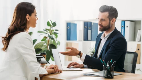schöner Berater im Anzug im Gespräch mit schönem Investor im Büro