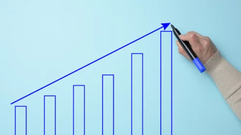 Graph with growing indicators and a female hand with a marker on a blue background. The concept of successful sales in business, inflation and rising prices