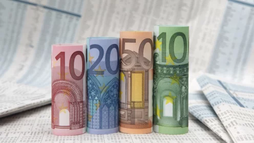 Gerollte Euro-Scheine vor einer Finanzzeitung