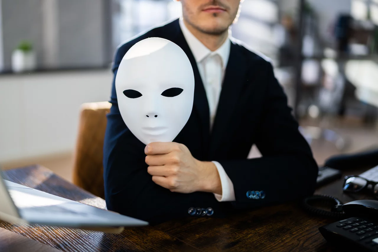 Betrüger mit weißer Maske in der Hand