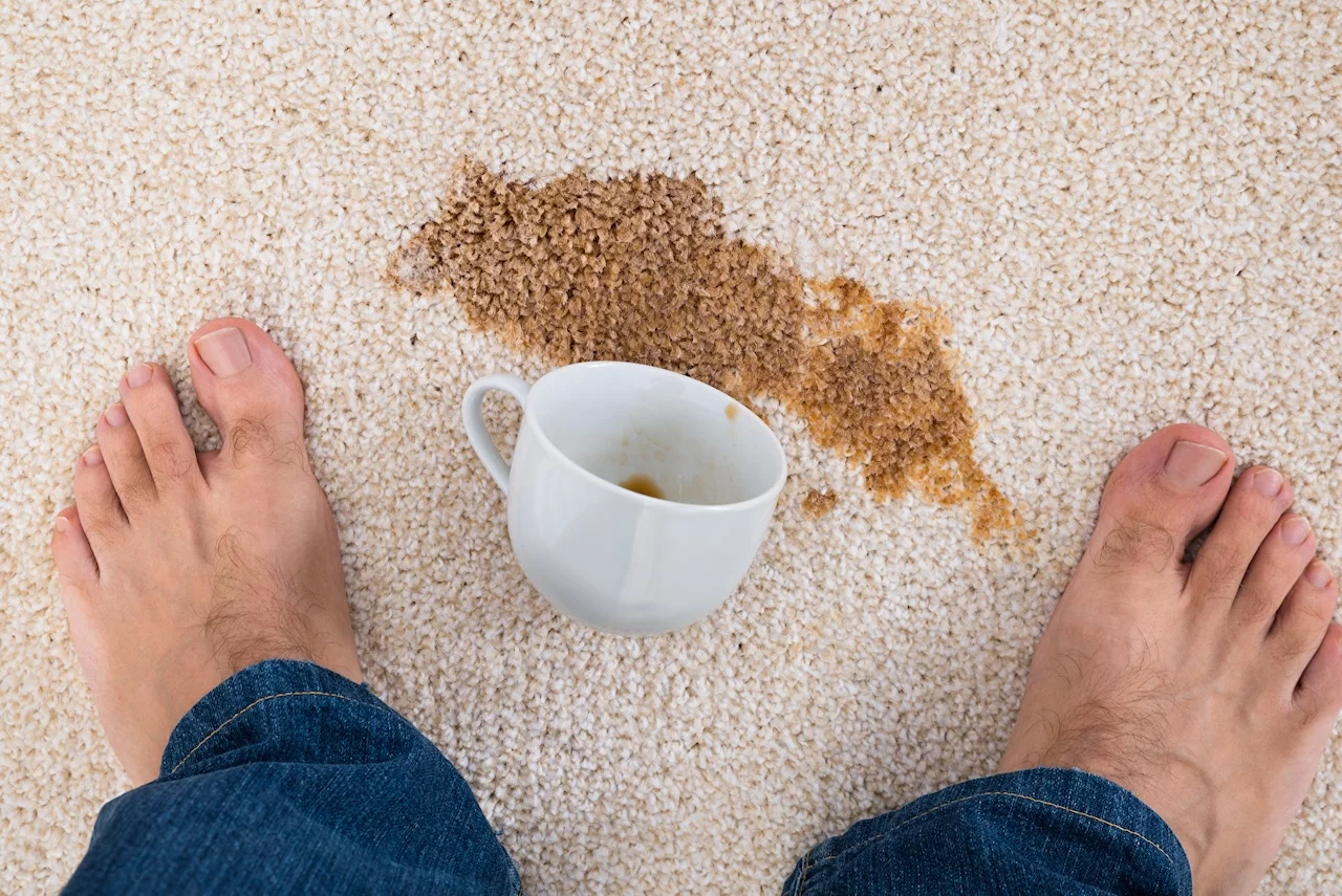 Mann steht vor einer kaffeetasse, in der nähe von kaffee verschüttet auf teppich