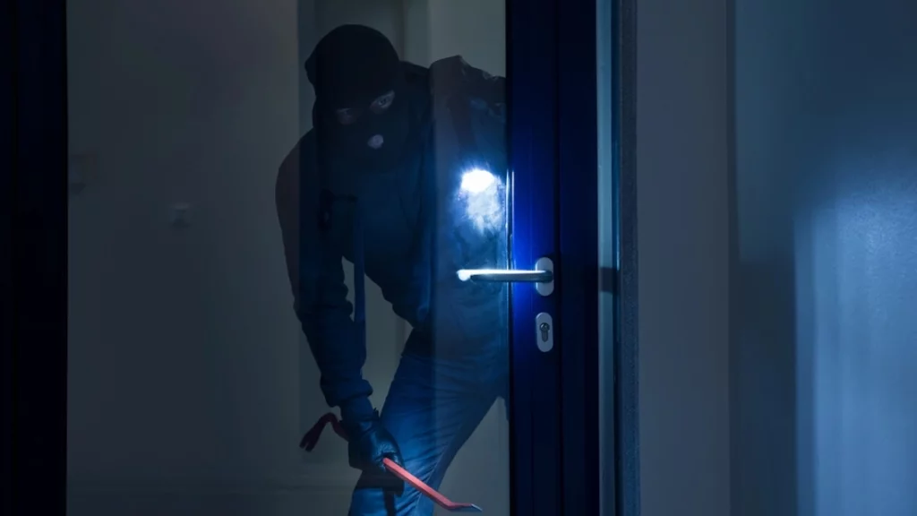 Einbruch bei Nacht, Einbrecher vor einer Glastür, Hausratversicherung, Versicherung
