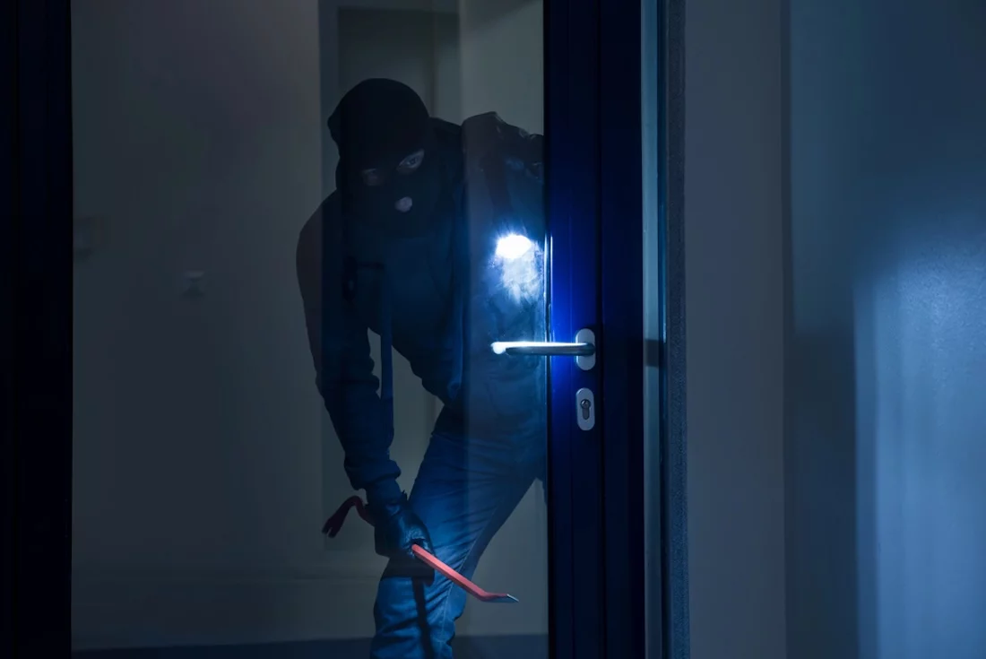 Einbruch bei Nacht, Einbrecher vor einer Glastür, Hausratversicherung, Versicherung