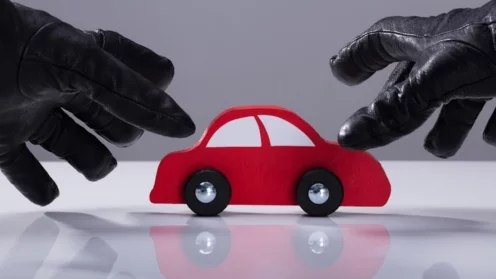 Autodiebstahl, Kfz, Nahaufnahme der Hand eines Diebes, der Handschuhe trägt und ein rotes Auto stiehlt