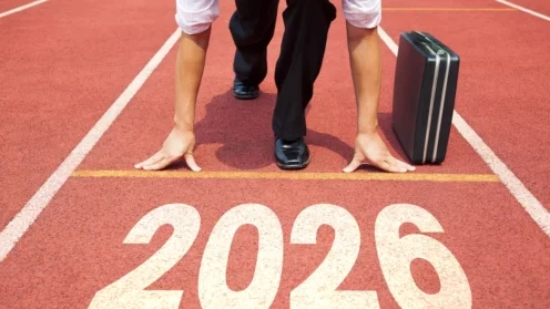 Konzept „Frohes neues Jahr 2026“. Geschäftsmann, der sich auf einer Leichtathletikbahn mit der Jahreszahl 2026 darauf vorbereitet, loszulaufen.
