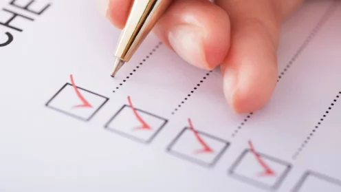 Cropped image of businesswoman writing on checklist