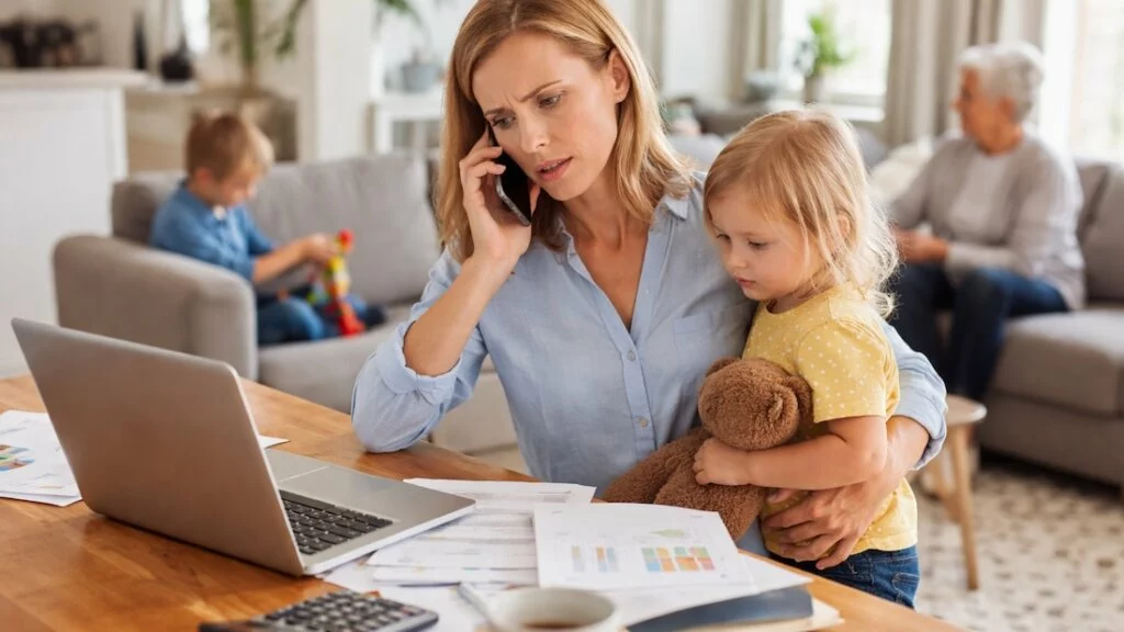Homeoffice, Care-Arbeit, Pflege, Gender Pension Gap, Gender Pay Gap, Mutter mit Kind am Laptop, im Hintergrund betreute ältere Frau