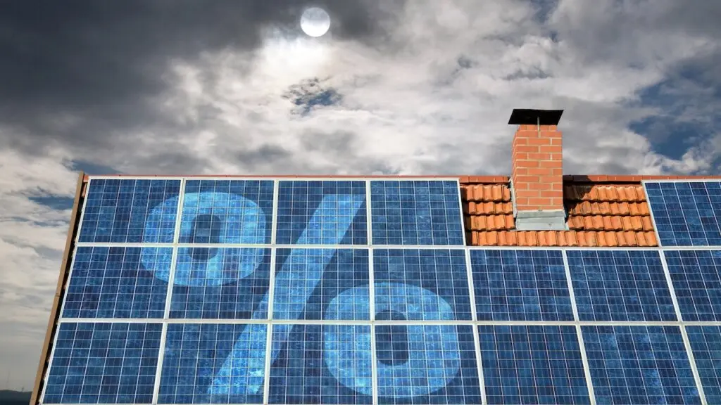 Photovoltaikmodule auf dem Dach eines Wohnhauses vor teils bewölktem Himmel, überlagert von einem Prozent-Symbol