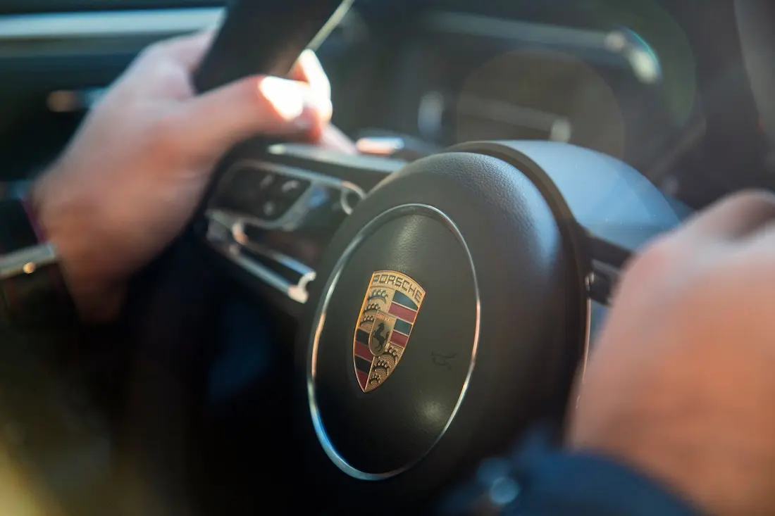 Ein Porschefahrer hält mit seine beiden Händen das Lenkrad