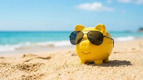 Gelbes Sparschwein mit Sonnenbrille am Strand
