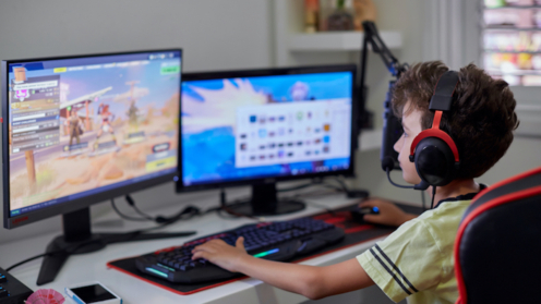 Teenager sitzt vor mehreren Monitoren und spielt "Fortnite"
