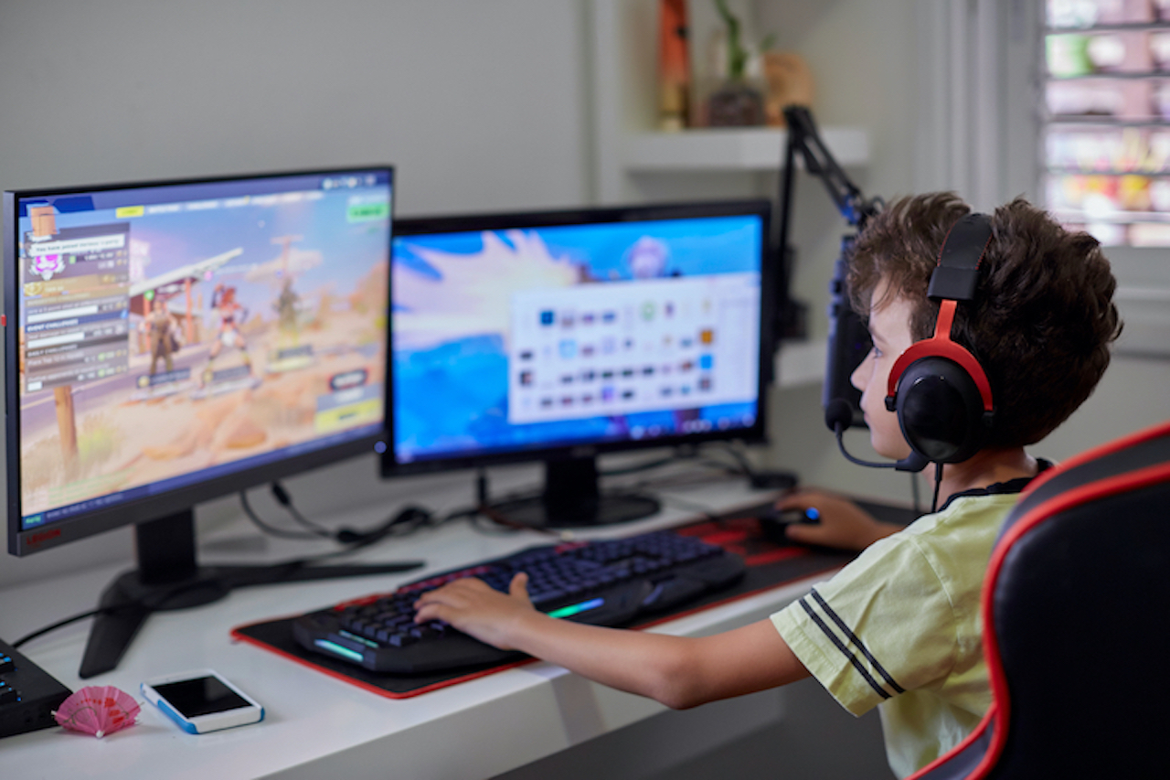 Teenager sitzt vor mehreren Monitoren und spielt "Fortnite"