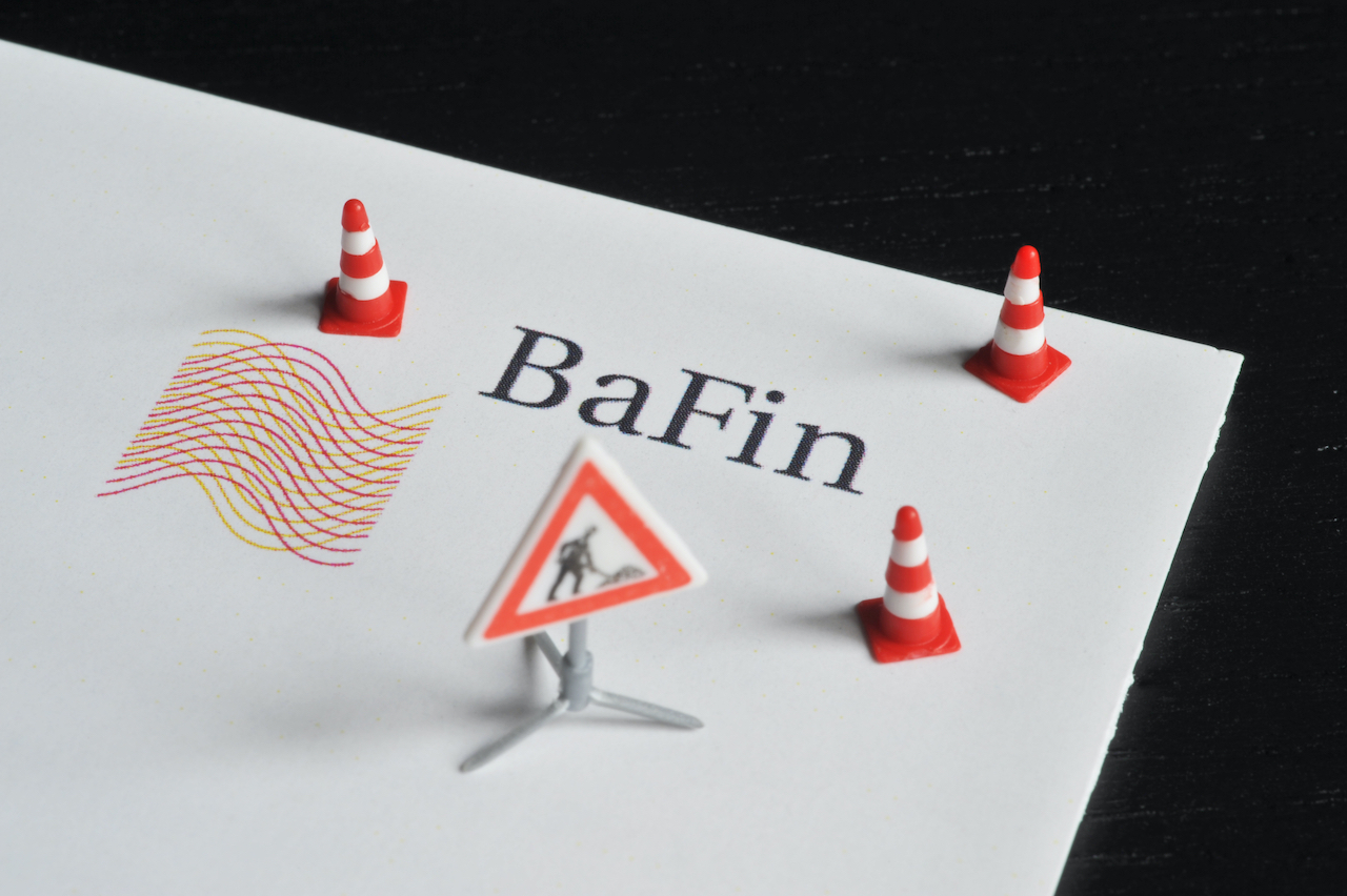 Logo der BaFin mit Baustellenschild und rot-weißen Hütchen