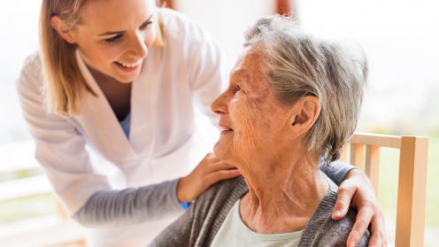 Eine Krankenschwester beugt sich zu einer älteren Frau