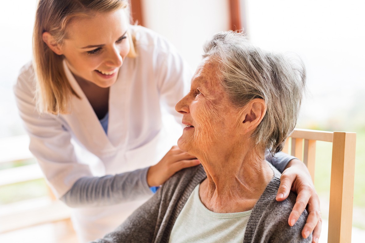 Eine Krankenschwester beugt sich zu einer älteren Frau