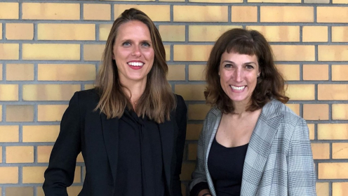 Sophie Kazmierczak und Tanja Volksheimer von der Bundesinitiative Impact Investing vor einer gelben Backstein-Wand..