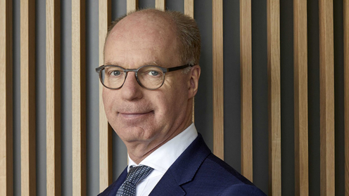 Lloyd Fonds CEO Achim Plate vor einer Wand mit senkrechten Holzleisten