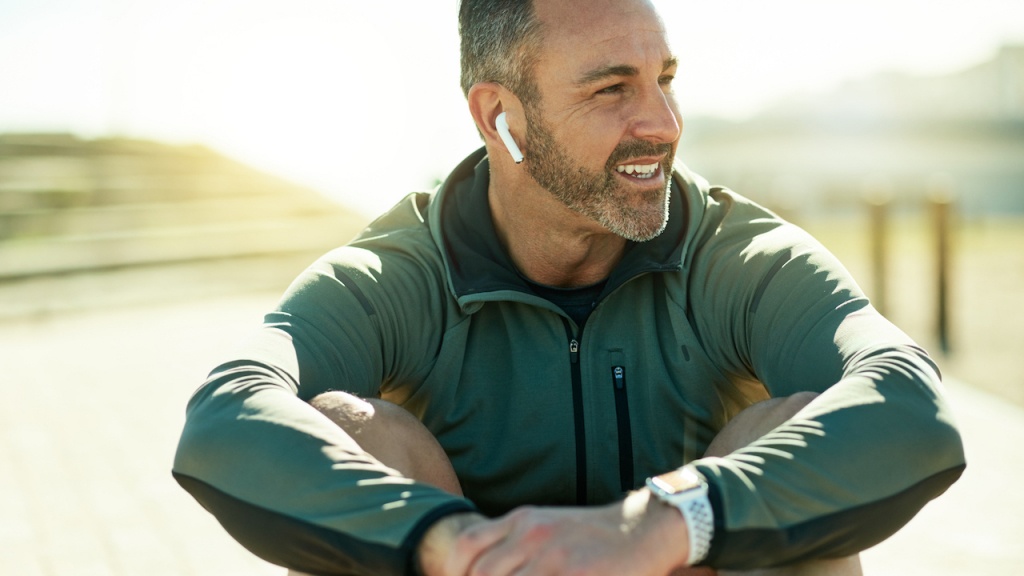 Foto von einem Mann, der während Ausdauertrainings eine Pause macht und Musik hört