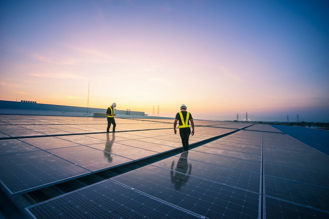 Zwei Arbeiter auf einem Dach mit Solar Anlagen