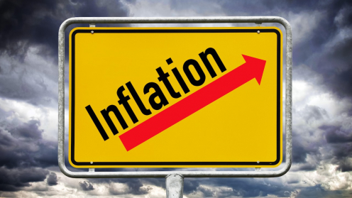 Ein gelbes Ortsschild mit der Aufschrift Inflation und einem roten Pfeil, der nach oben zeigt