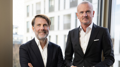 Deutsche Finance Thomas Oliver Müller (rechts) und Dr. Sven Neubauer vor dem Hintergrund des Blicks aus einem Bürofenster.