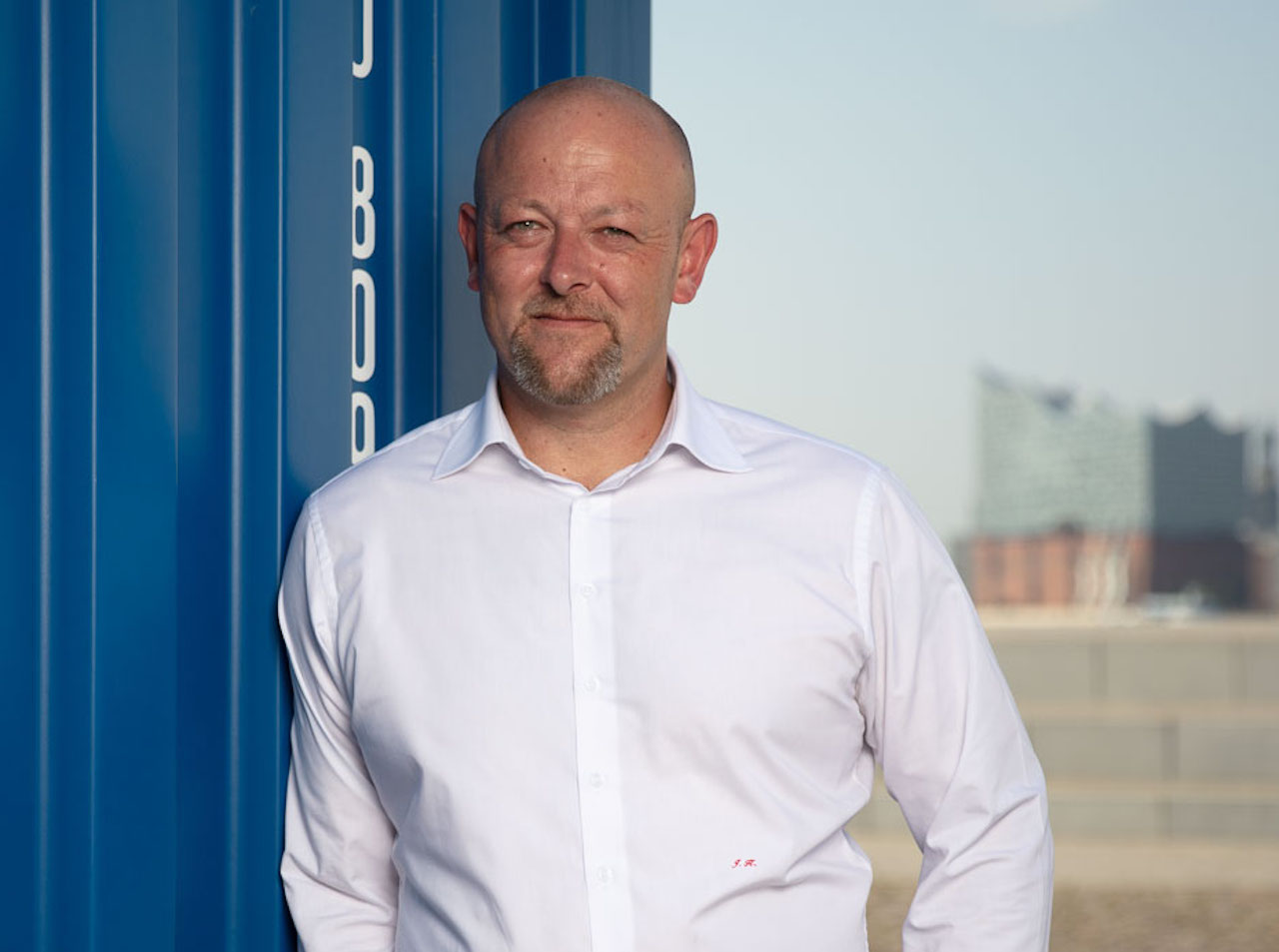Jürgen Kestler, Geschäftsführer Solvium Capital Vertriebs GmbH, lehnt an einem Container. Im Hintergrund die Elbphilharmonie in Hamburg.