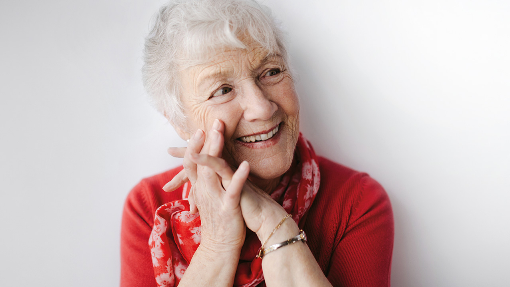 Mature, white haired woman on white studio background. She is cute, healthy and vibrant.
