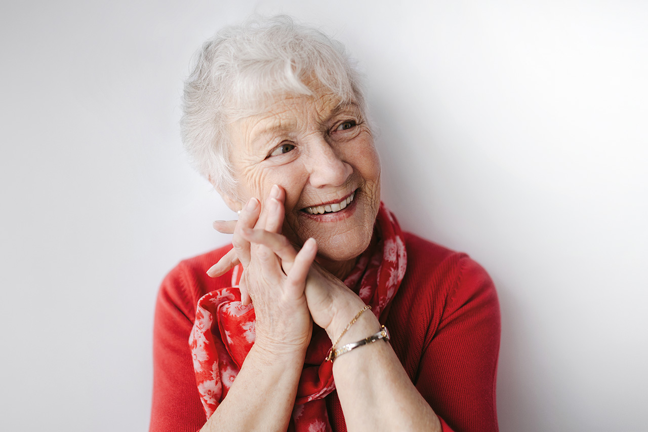 Mature, white haired woman on white studio background. She is cute, healthy and vibrant.