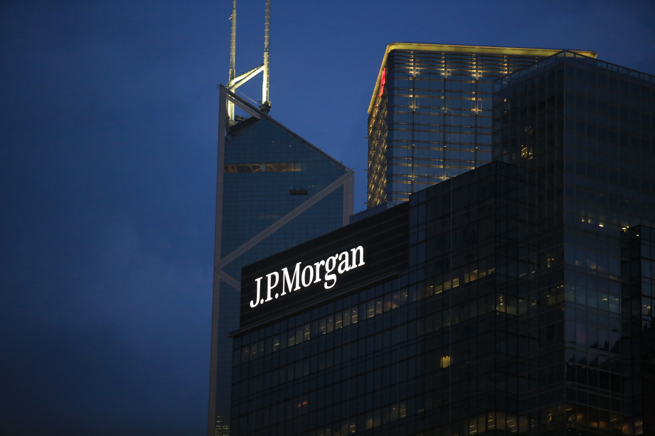das JP Morgan Gebäude ist ein Hochhaus. Es steht im Dunkeln und man sieht die JP Morgan Schrift hell erleuchtet