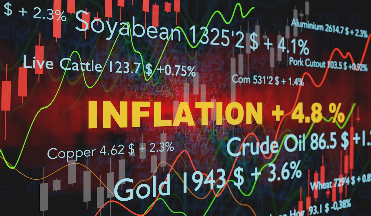 Die Schrift Inflation sticht orange hervor im Hintergrund sieht man Aktienkurse