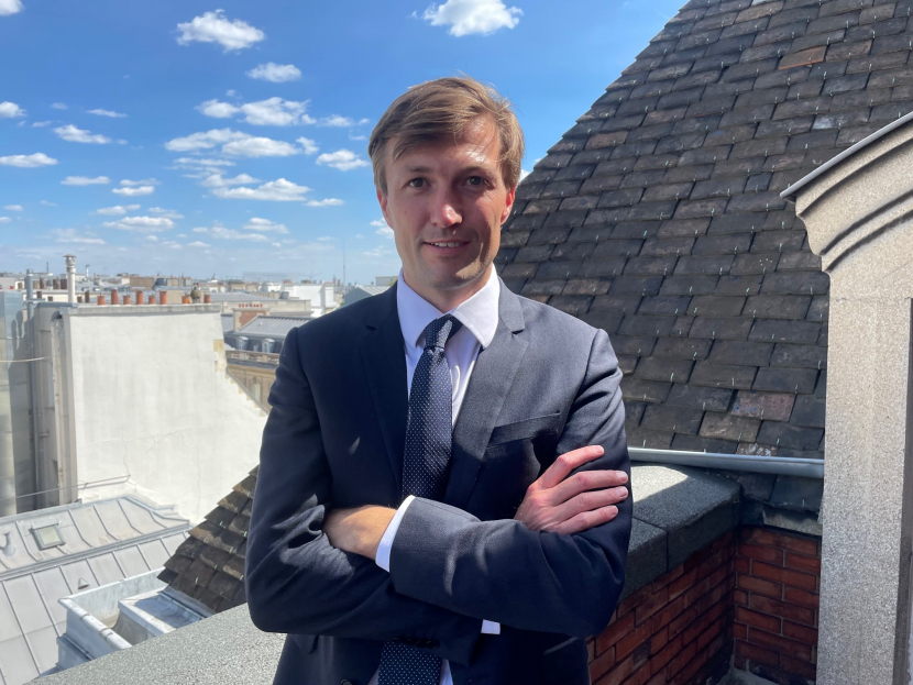 Ein Mann steht mit verschränkten Armen auf der Terrasse eines Hauses