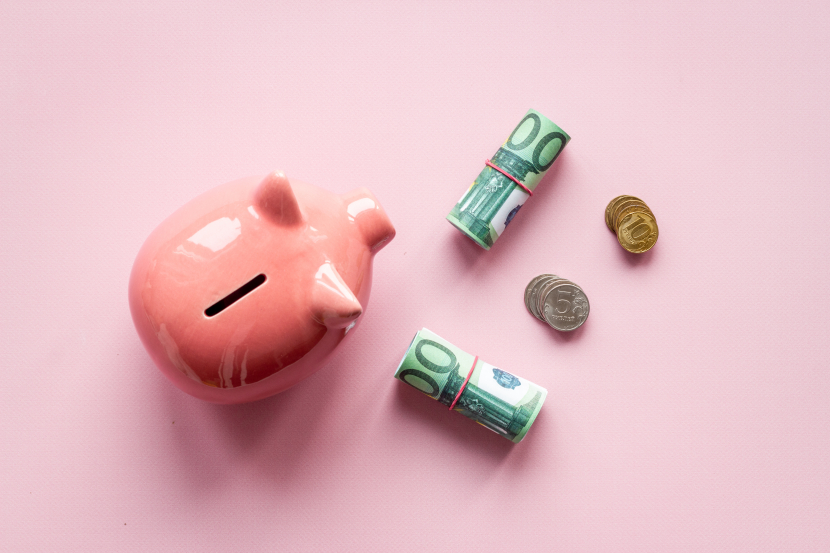 Ein Sparschwein von oben und Bargeld, das daneben liegt