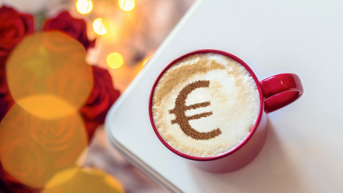 Capucchino-Taste mit einem Eurozeichen aus Kakaopulver auf dem Milchschaum