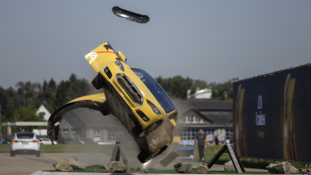 Ein gelber Tesla fliegt bei einem Crash seitlich in die Luft