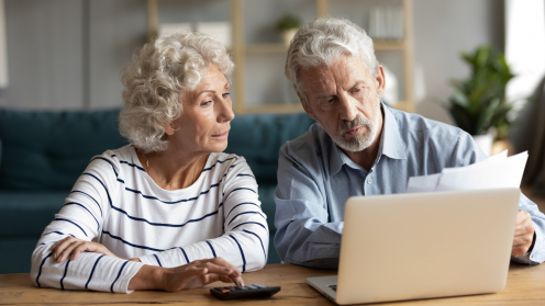 Ein älteres Ehepaar sitzt an einem Tisch und schaut auf Unterlagen