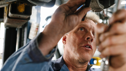 Handwerker arbeitet an Unterboden von Auto