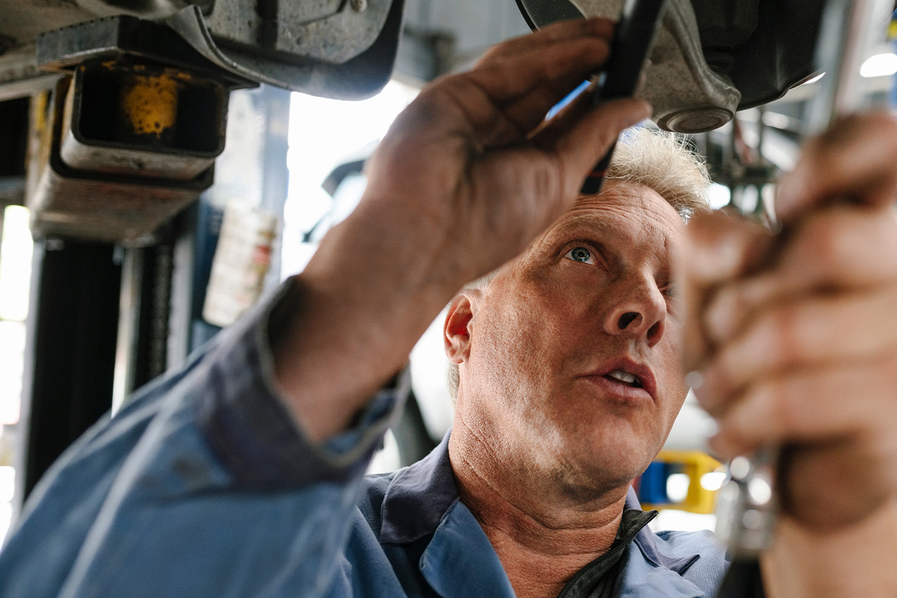 Handwerker arbeitet an Unterboden von Auto